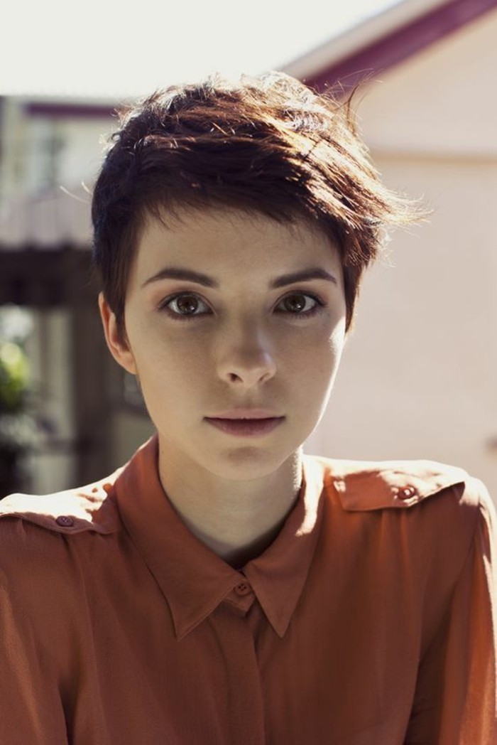 short haircuts, young woman with brown hair and short pixie cut, bangs brushed to one side, wearing orange shirt