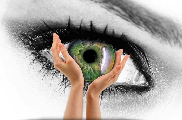 rarest eye color, collage featuring two female hands holding a green iris, on a black and white background, featuring a large eye