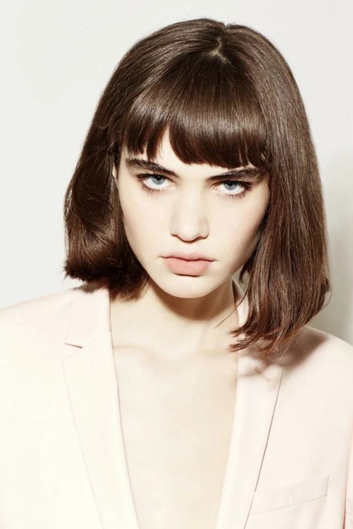 hairstyles for short hair, pale woman with brown shoulder-length hair and bangs, wearing white oversized blazer