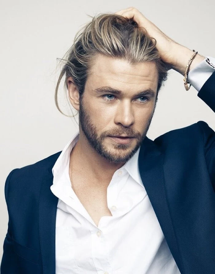 medium length hairstyles, Chris Hemsworth holding his hair with one hand, wearing dark blue blazer and white shirt