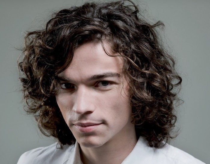 shoulder length haircuts, smiling curly man in white shirt, messy brown hair