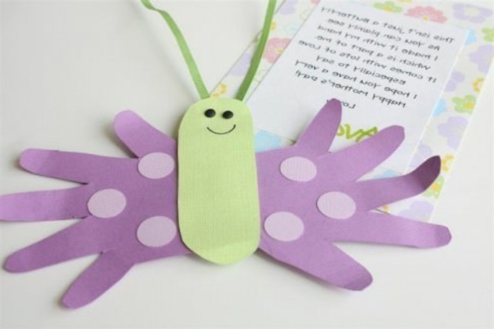 easy kids crafts, smiling butterfly made from pale green and violet paper, placed near a letter