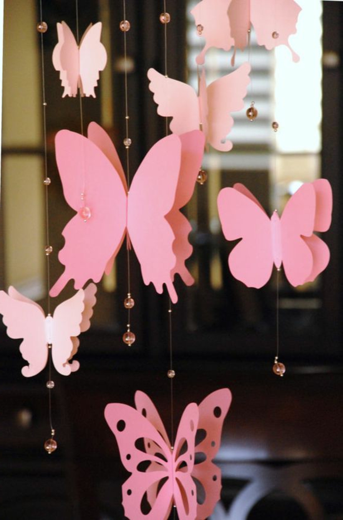 diys to do with friends, decoration made from differently shaped, pink butterfly paper cutouts, tied to thin strings, decorated with tiny clear pink beads