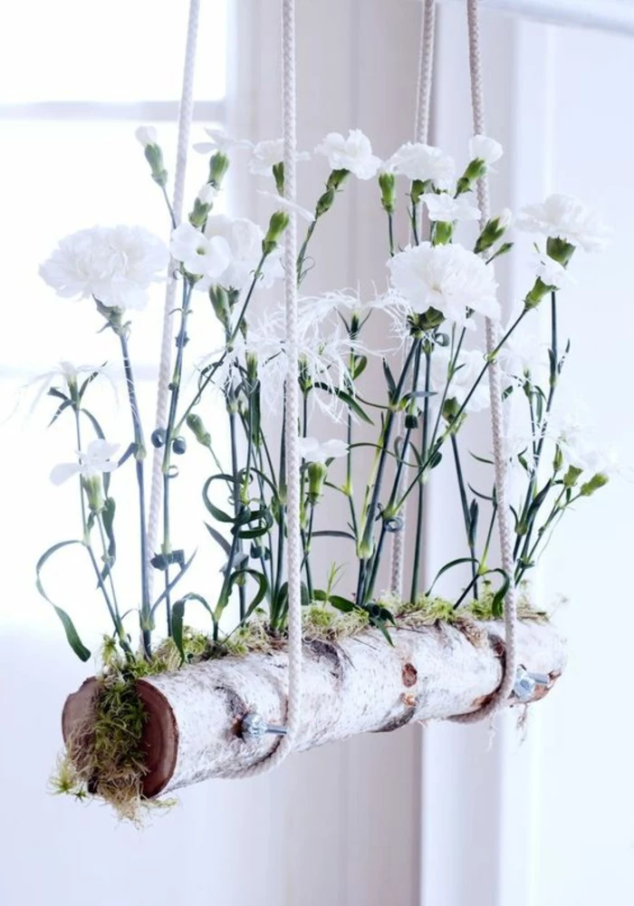 summer crafts, hanging planter made from white birch, containing green moss and white planted carnations