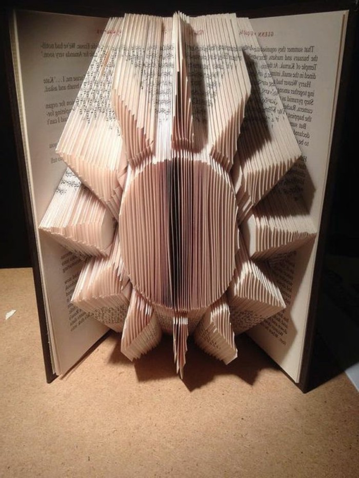 sun shape made from folded pages, inside an open book, with dark hard covers