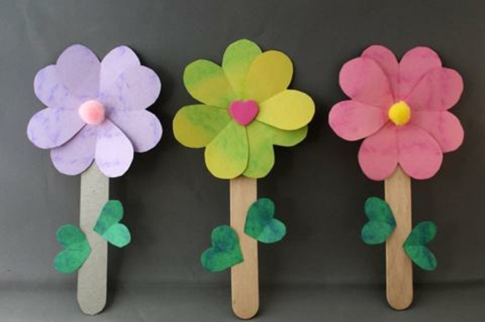 diy art projects, three flowers made of paper in pale violet, green and red, attached to stalks made from ice cream sticks, with small green paper leaves