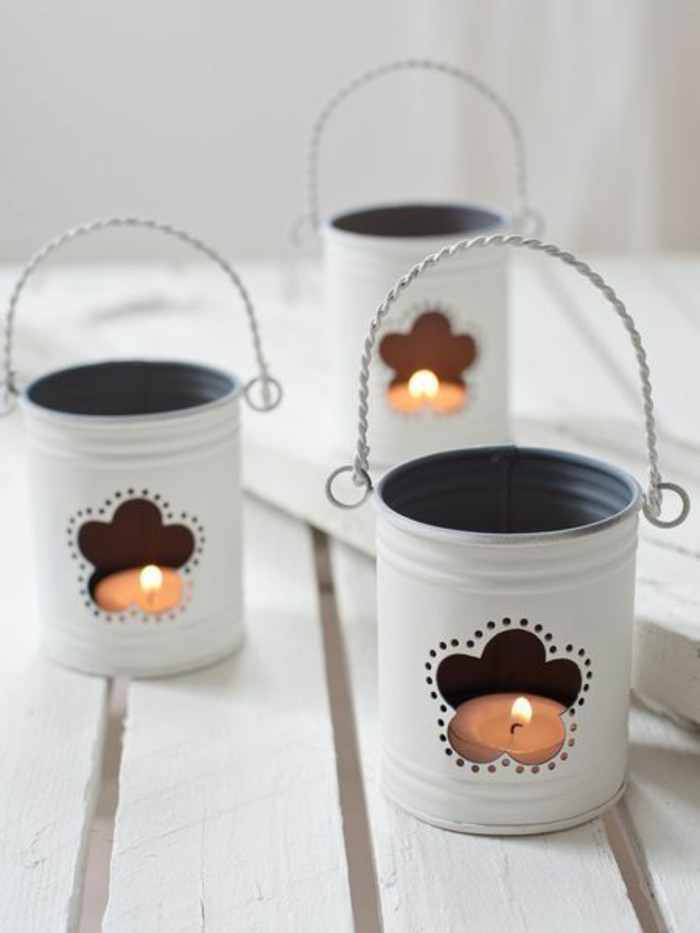 tin cans for crafts, three tin cans painted white, whit twisted wire handles, and flower shaped holes, containing small lit candles