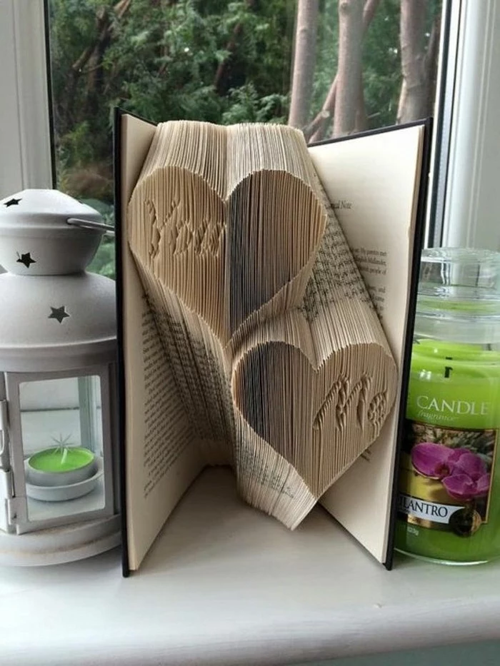 two heart shapes, with the inscription you and me, made from folded pages, inside a vintage book, with black hard covers