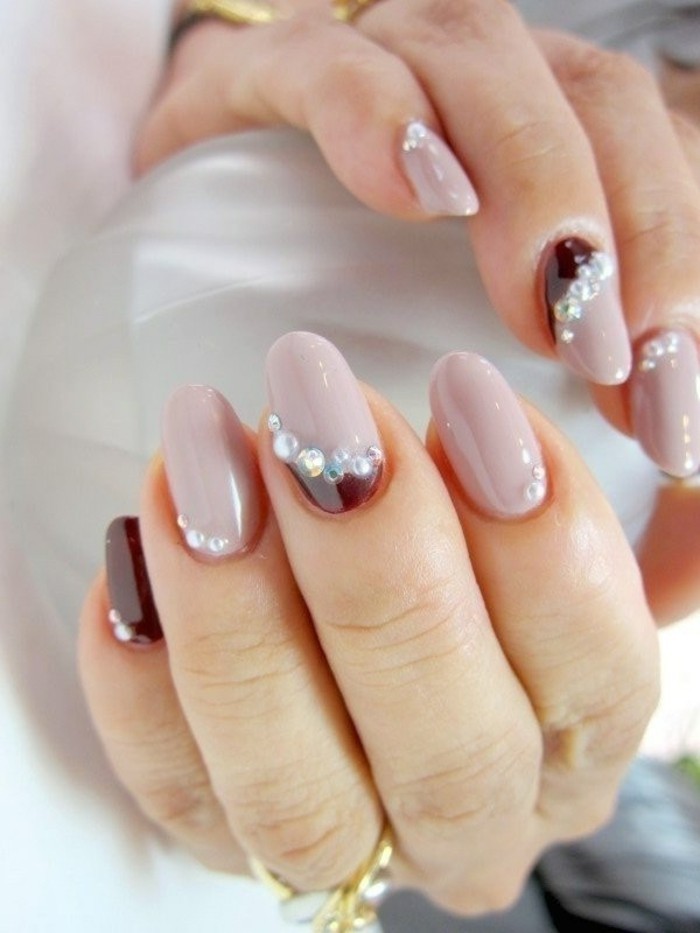round nails colored in light and dark plum nail polish, decorated with silver rhinestones