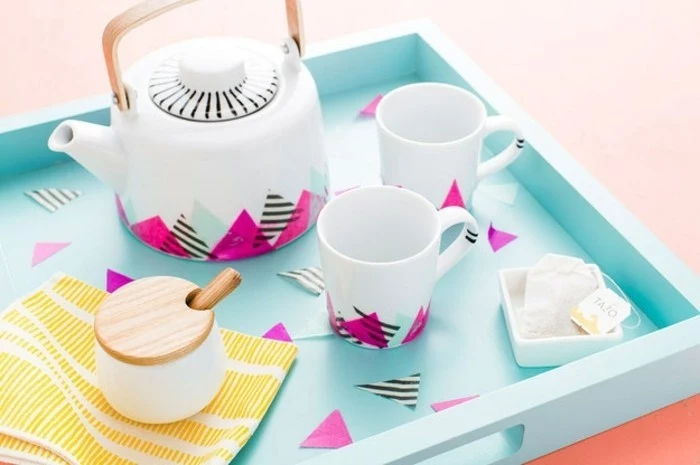 best friend gift ideas, white tea pot and two mugs, decorated with triangular bits of colorful paper, on pale blue tray