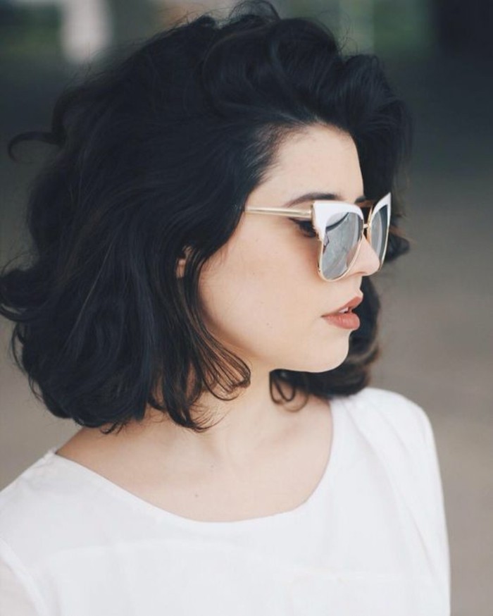 cute short haircuts, woman with short voluminous black wavy hair, wearing white top, and retro sunglasses with white frames