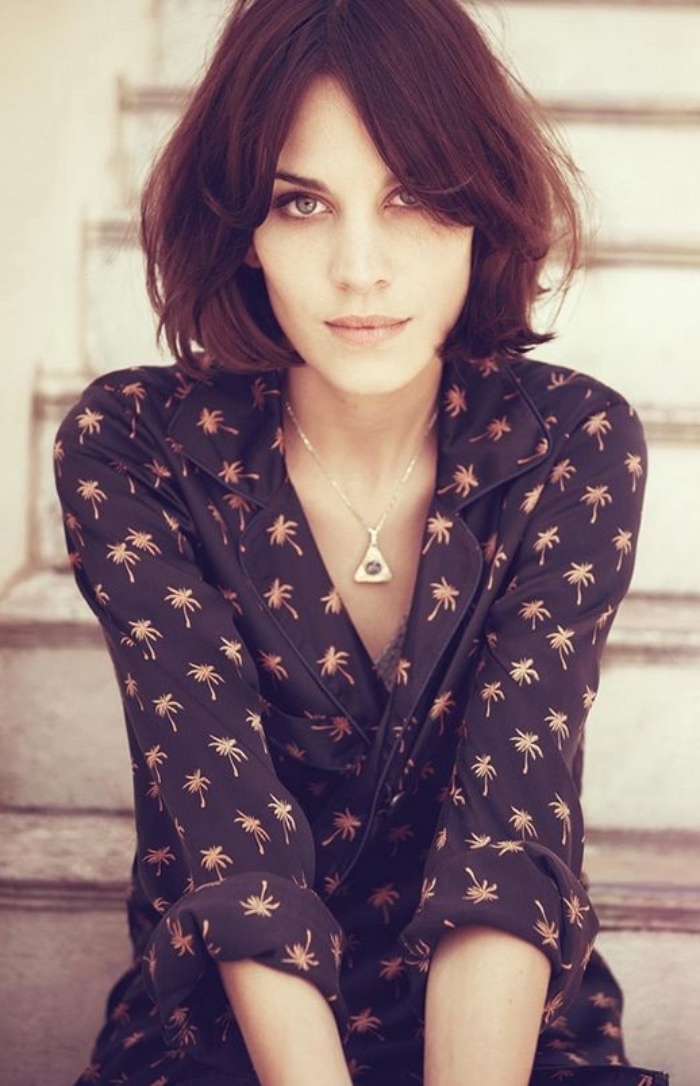 alexa chung wearing black shirt, with golden palms pattern, hair styled in messy bob haircut, with wavy ends