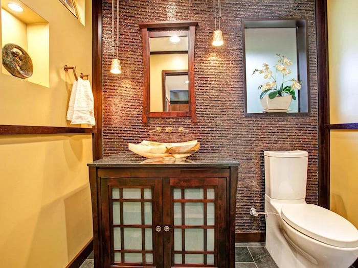 bathroom decorating ideas, toilet with two yellow walls, and a third wall decorated with brown mosaic, wooden beams and trims, large wooden cupboard with unusual sink, modern white toilet