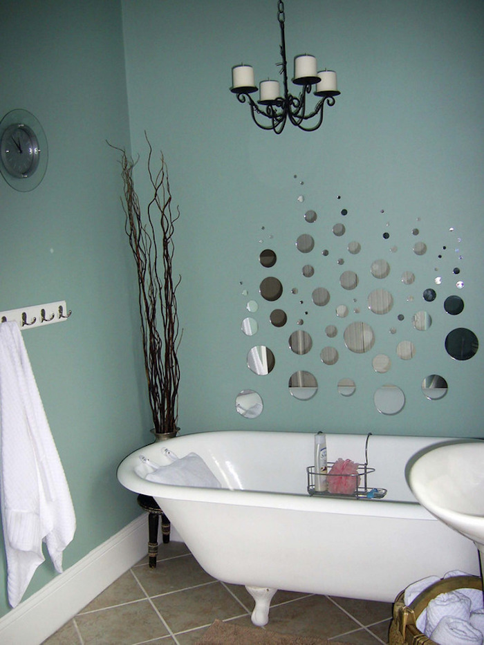 bathroom decorating ideas, duck's egg blue walls, one decorated with many round mirror segments, light brown floor tiles, white bathtub and tall dried plant in corner