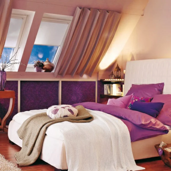 curtains ideas, room with purple paneling, bed in white and purple, with many cushions, sloped window with light brown, gathered curtains and pale window covers