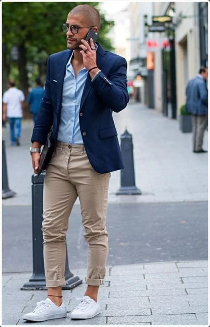 beige carrot pants, combined with white sneakers, and an ankle bracelet, worn by man in dark navy blazer, over pale blue shirt, business casual dress code 