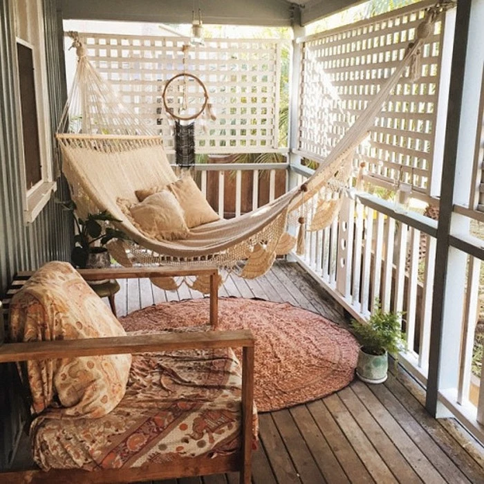 pale beige hammock, with crochet details and pillows, hanging over round oriental rug, near wooden chair with cover and dreamcatcher, covered patio ideas