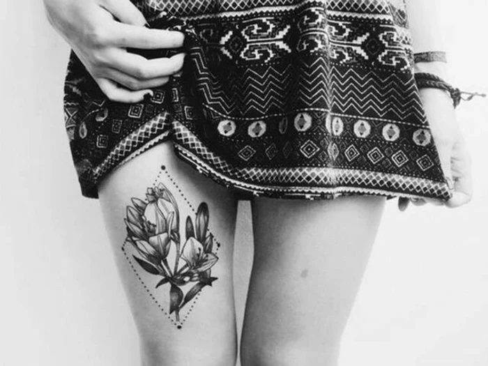 woman with short, patterned skirt, with an image of two crocuses, inside a dotted diamond-shape, tattooed above her knee