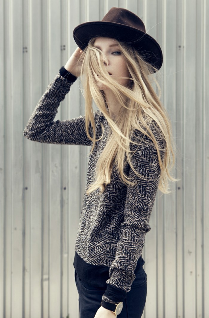 casual clothes, slim young woman with long blonde hair, wearing black and white patterned sweater, black skinny trousers, and a dark maroon felt hat