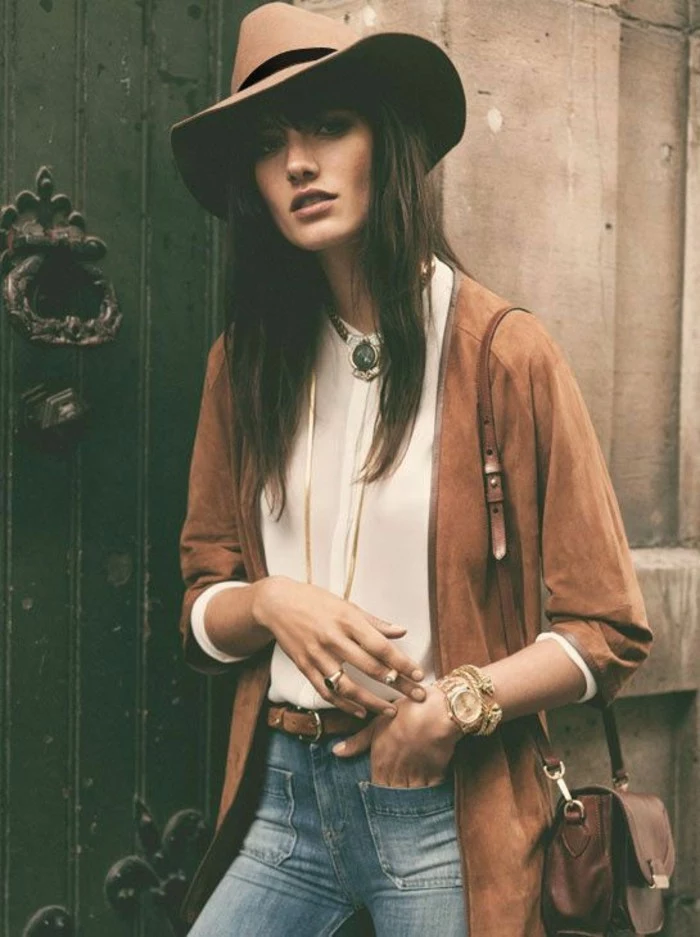 casual business attire, camel colored suede cardigan, worn over pale cream shirt, and jeans with front pockets and belt, by brunette woman in pale beige felt hat