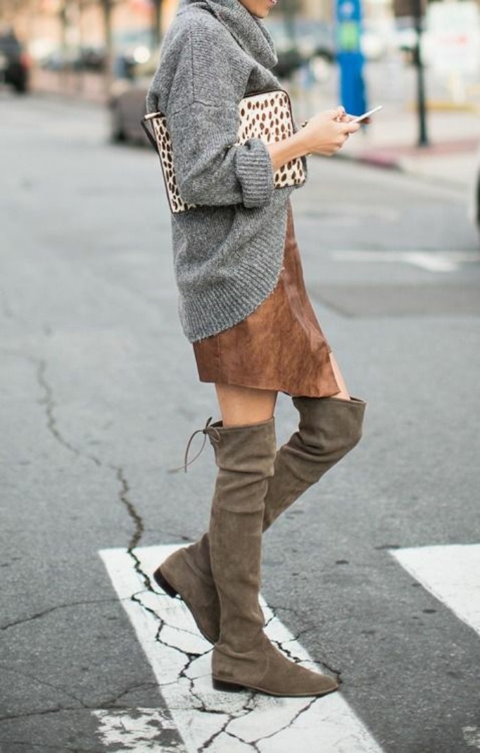 business casual for young women, grey oversized turtleneck jumper, over brown suede mini skirt, worn with beige over the knee boots, by woman holding large animal-print clutch