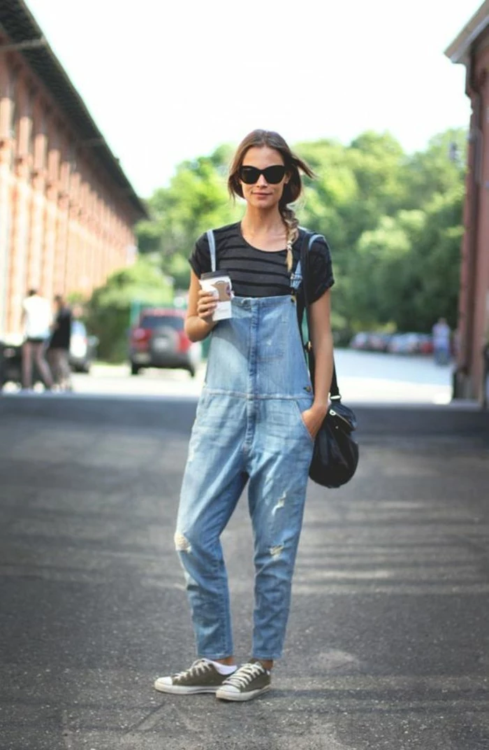 grey and black striped t-shirt, and baggy pale denim overalls, worn by brunette woman with braided hair, with sunglasses and black leather bag