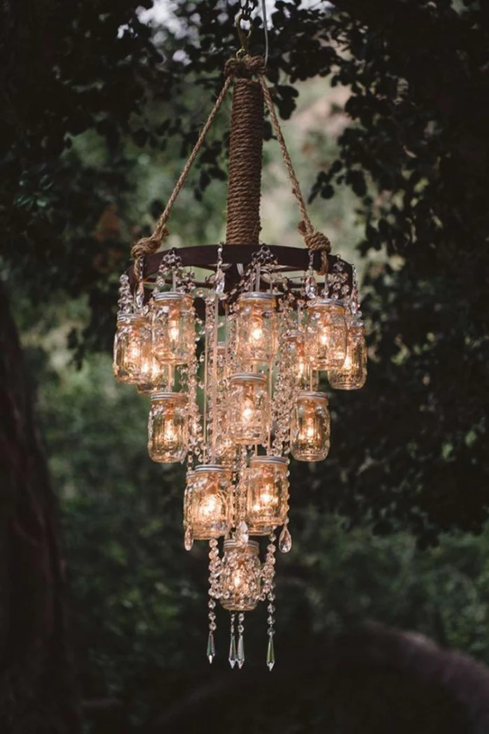 mason jar crafts, chandelier made of mason jars, containing lit fairy lights, with crystal decorations, hanging from a tree