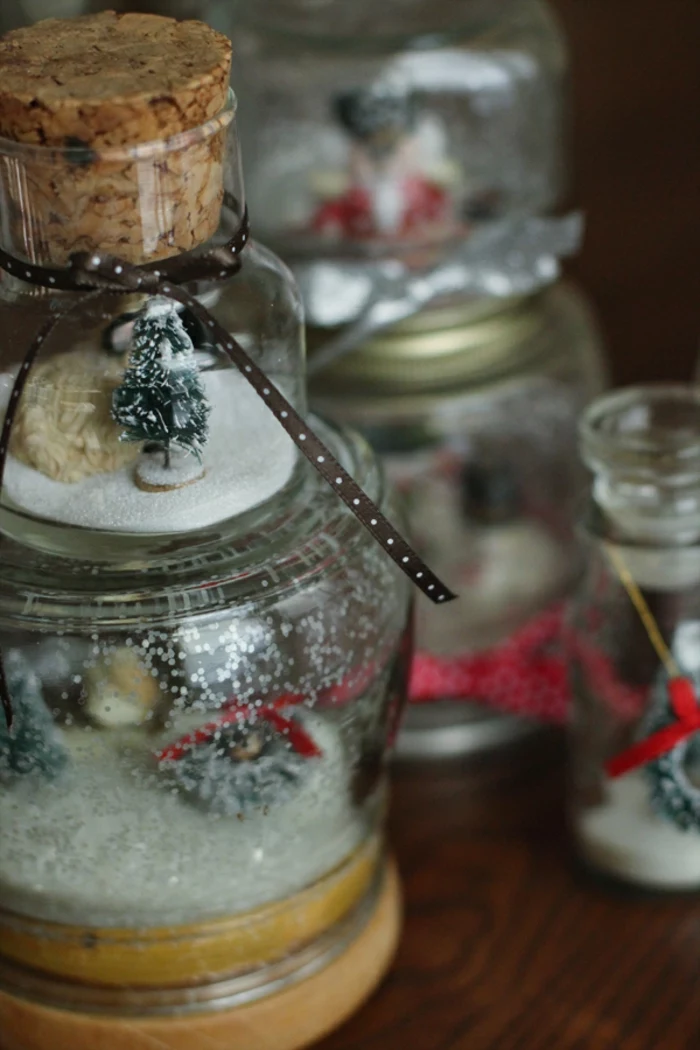 christmas mason jars, several jars transformed into snow globes, containing fake snow, and little christmas tree figurines