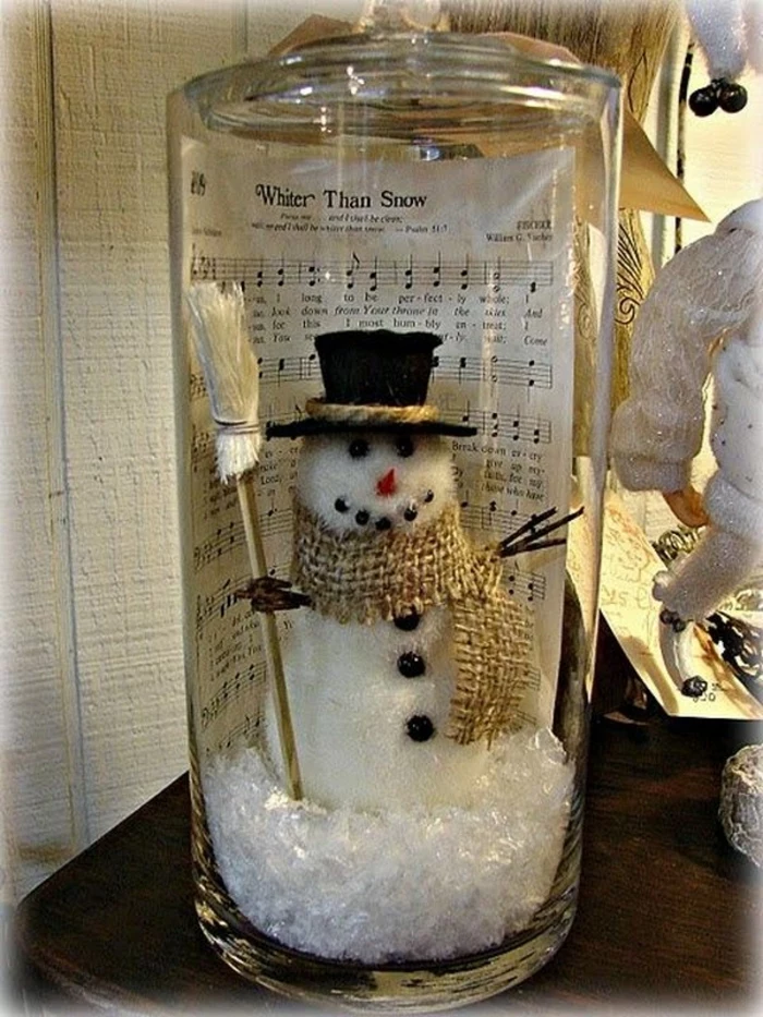 christmas mason jars, large clear jar, containing fake snow, a snowman figurine, and a sheet music page