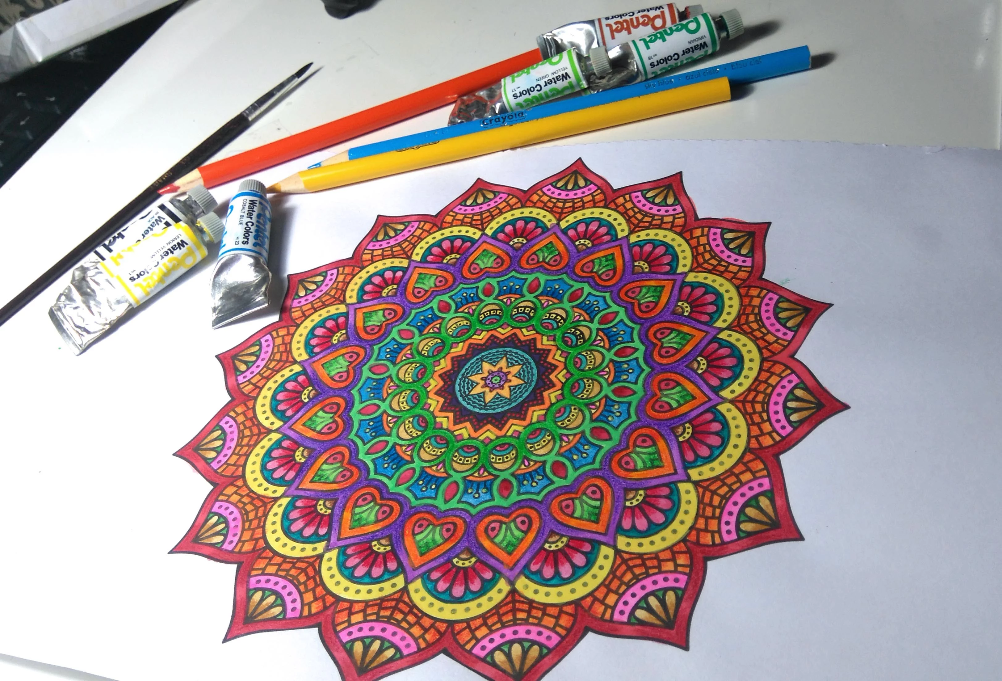flower mandala in yellow, orange and red, pink and blue, craft ideas, colored pencils and tubs of paint in background