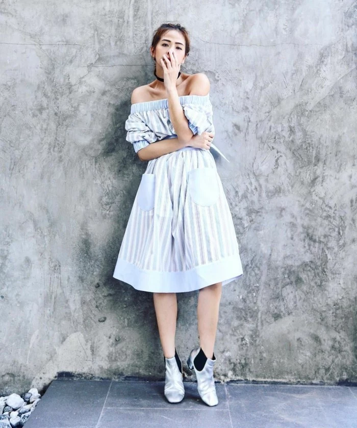 women business casual, pale blue and white, striped knee-length off-shoulder dress, worn by woman with tied back hair, wearing black chocker necklace, and silver chelsea-style ankle boots