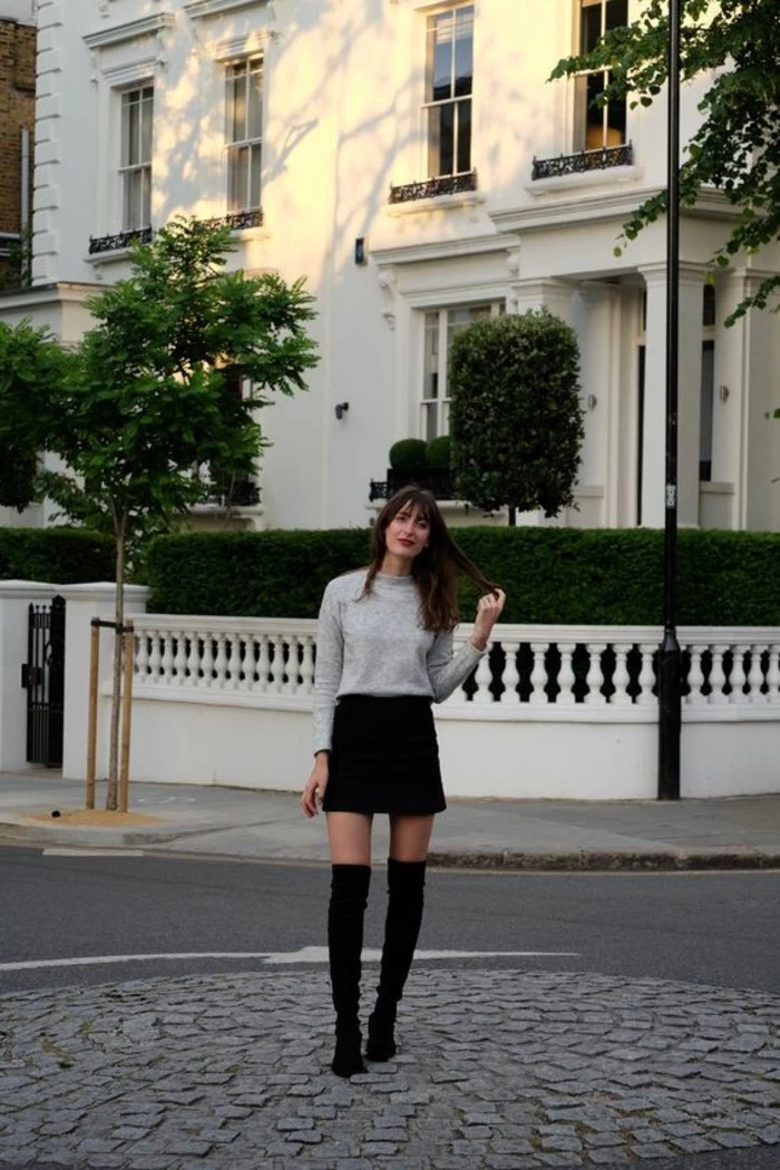 casual business attire, woman with long brunette hair and bangs, wearing pale grey sweater, black mini skirt, and black over the knee high-heeled boots