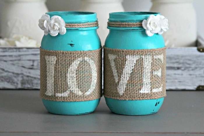 mason jar crafts, two jars painted in turquoise, with small white roses, tied around them with string, decorated with burlap, with the world love written on it