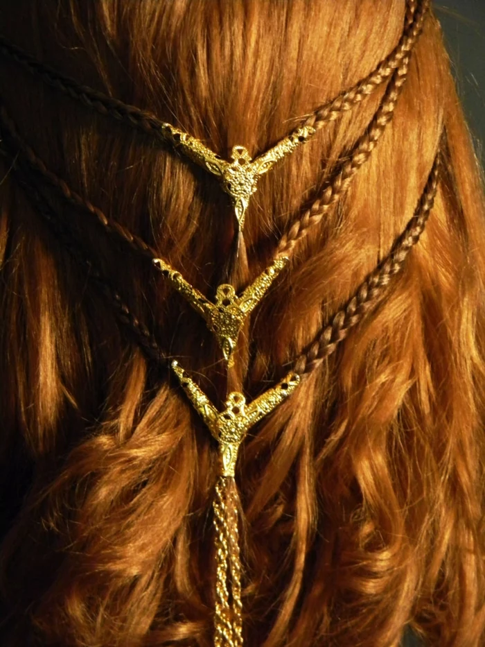 medieval braids, close up of wavy ginger hair, with two rows of small braids, joining in the middle, decorated with gold ornaments