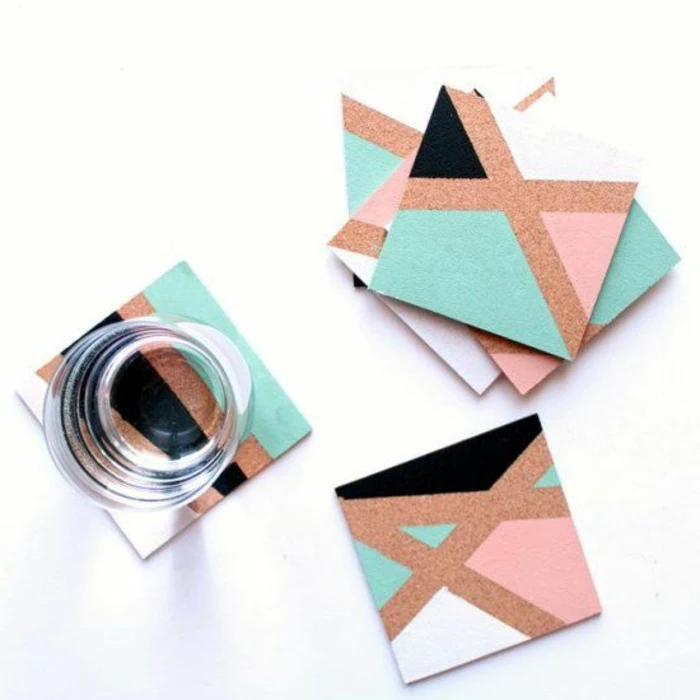 square cork coasters, decorated with asymmetrical blue and pink, and black and white shapes, diy craft projects, one clear glass