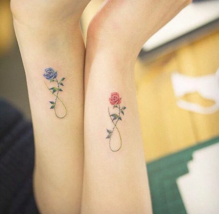 botanical tattoo, two arms with matching rose tattoos, one blue and one red, with identical stalks, twisted to make the sign for infinity