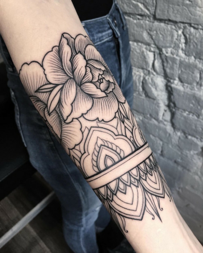 flower tattoos, hand with half-sleeve tattoo, outlined with black ink, featuring floral motives, and symmetrical buddhist details