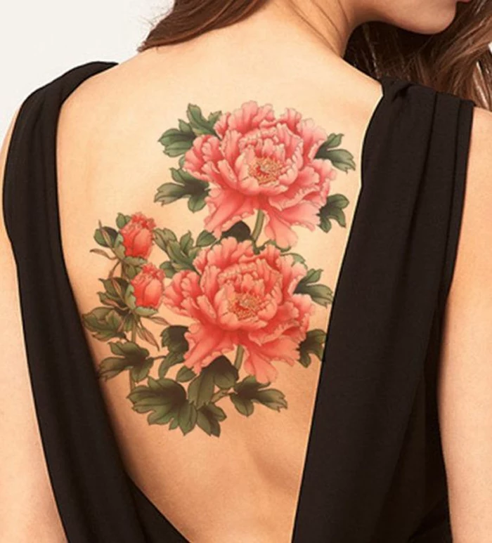 brunette woman wearing a black, open back top, revealing a large tattoo, of two blossoming pink-red peonies, with two buds and lots of green leaves