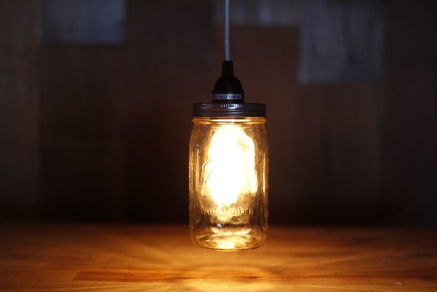 lit lamp, made from shining lighbulb, inside a clear mason jar, hanging from black cable