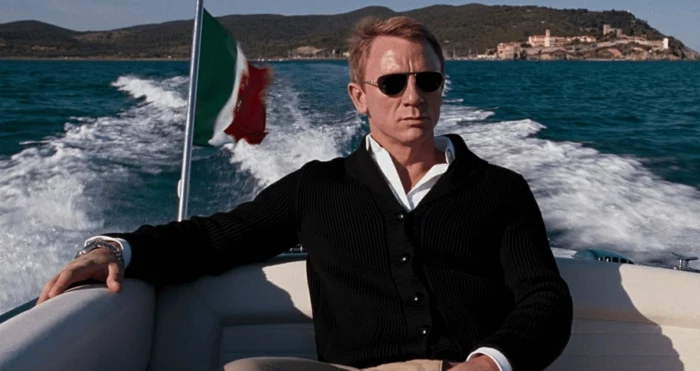 daniel craig with aviator sunglasses, business casual men, dressed in a black blazer, over white shirt, riding in a speedboat