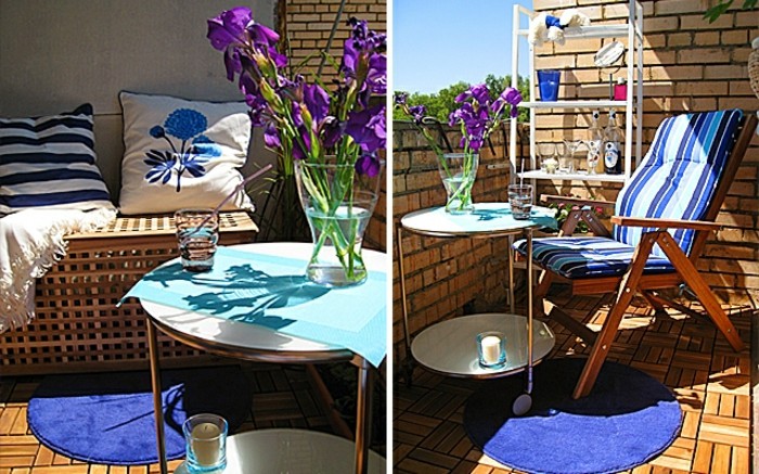 brick walls and wooden floor, wooden settee with two cushions, bright blue round rug, and round table with clear vase, containing purple flowers