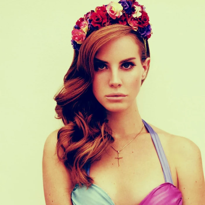medieval hairstyles, red-haired lana del ray, with hairstyle inspired by the middle ages, curled and falling over one shoulder, and decorated with colorful flower crown