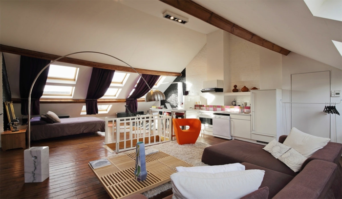 living-room-curtains-ideas-spacious-attic-room-sloped-ceiling-with-two-visible-wooden-beams-brown-couch-wooden-table-and-floors-three-windows-with-dark-brown-curtains window treatment ideas, large living room with sloped ceiling, three windows with dark brown curtains, sofas and a table