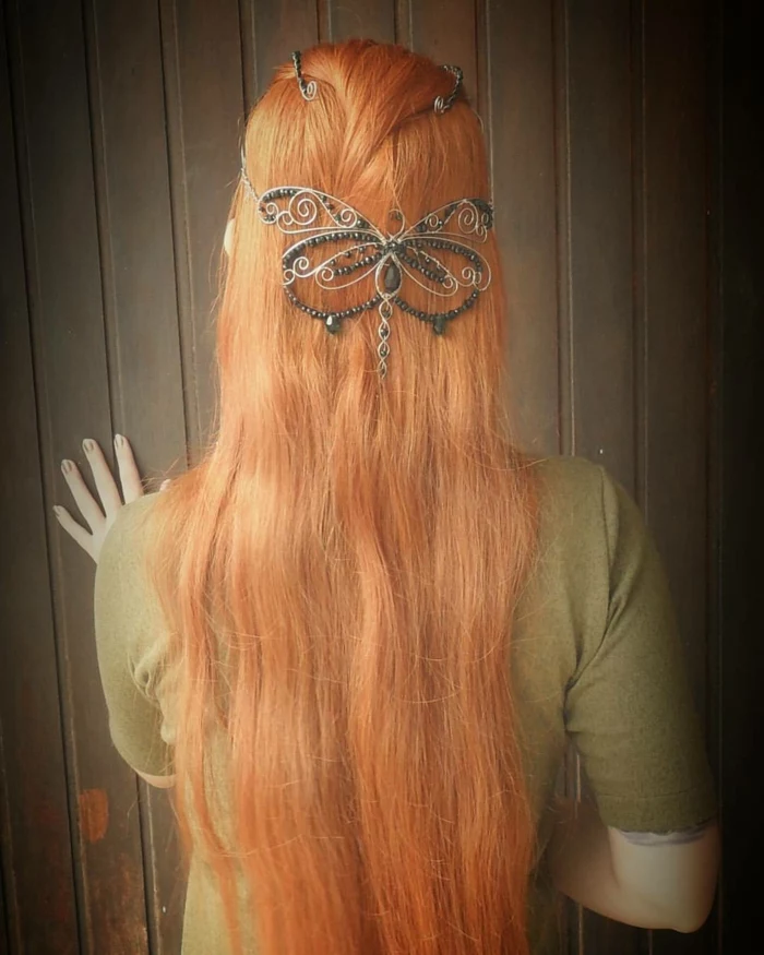 medieval hairstyles, long ginger hair, decorated with a wire butterfly ornament, featuring many black beads, worn by woman in pale, olive green t-shirt