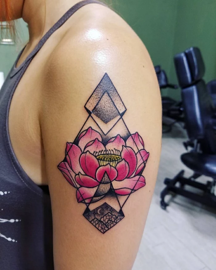 lotus flower tattoo, close up of a woman's shoulder, with a floral tattoo in pink and yellow, decorated with geometric patterns, on her upper arm