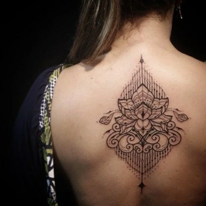 lotus flower tattoo, woman with bare back, and a symmetrical, buddhist lotus tattoo, with swirls and lines, all outlined in black ink