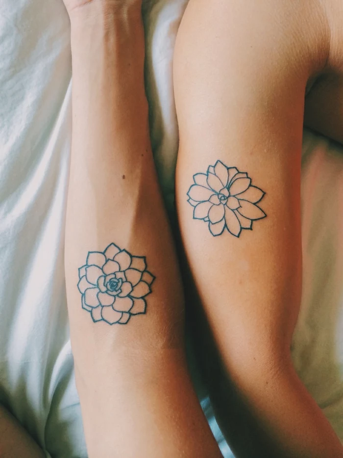lotus flower tattoo, two bare arms, with similar flower tattoos, outlined with black ink