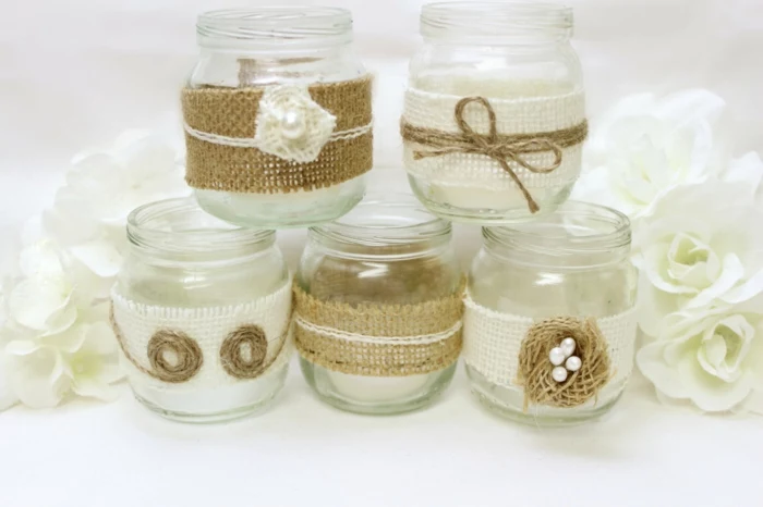 mason jar decorations, five small jars, decorated with white and beige burlap, with string and pearl details, white roses in the background