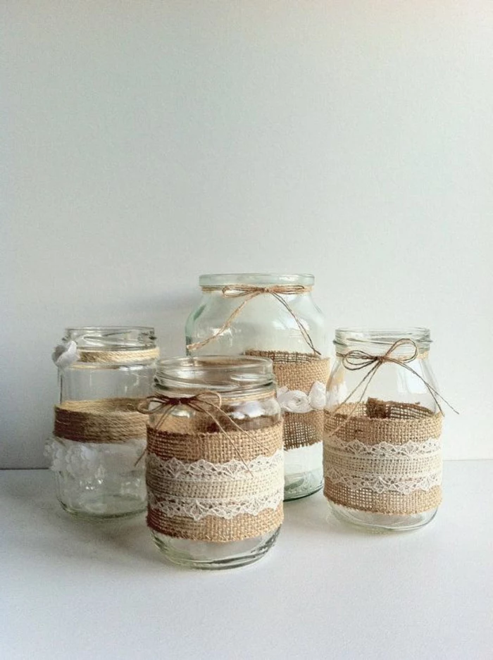 mason jar centerpieces, four different clear jars, decorated with burlap and white lace, each sporting a string bow