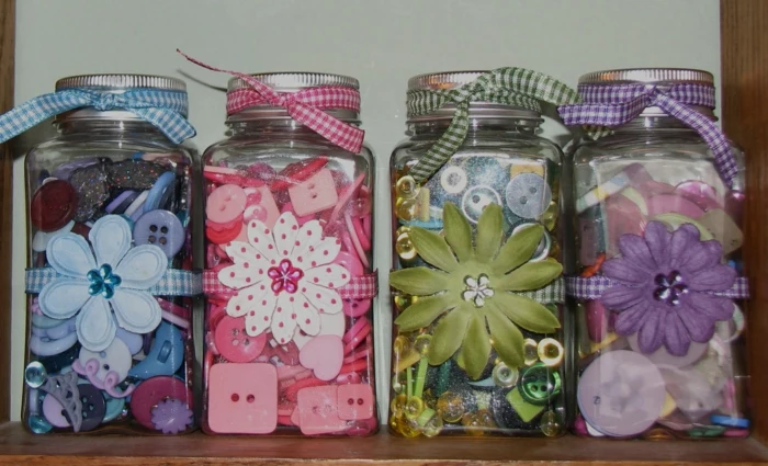 mason jar decorations, four jars decorated in different colors, blue and pink, green and violet, each containing buttons and bands in a corresponding color